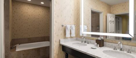 A modern bathroom with two sinks, a large mirror, and a bathtub.