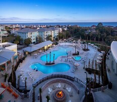 A resort with multiple swimming pools, lounge areas, and a fire pit.