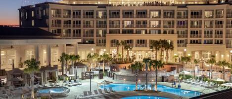 A hotel with multiple swimming pools, outdoor seating areas, and a large building with balconies.
