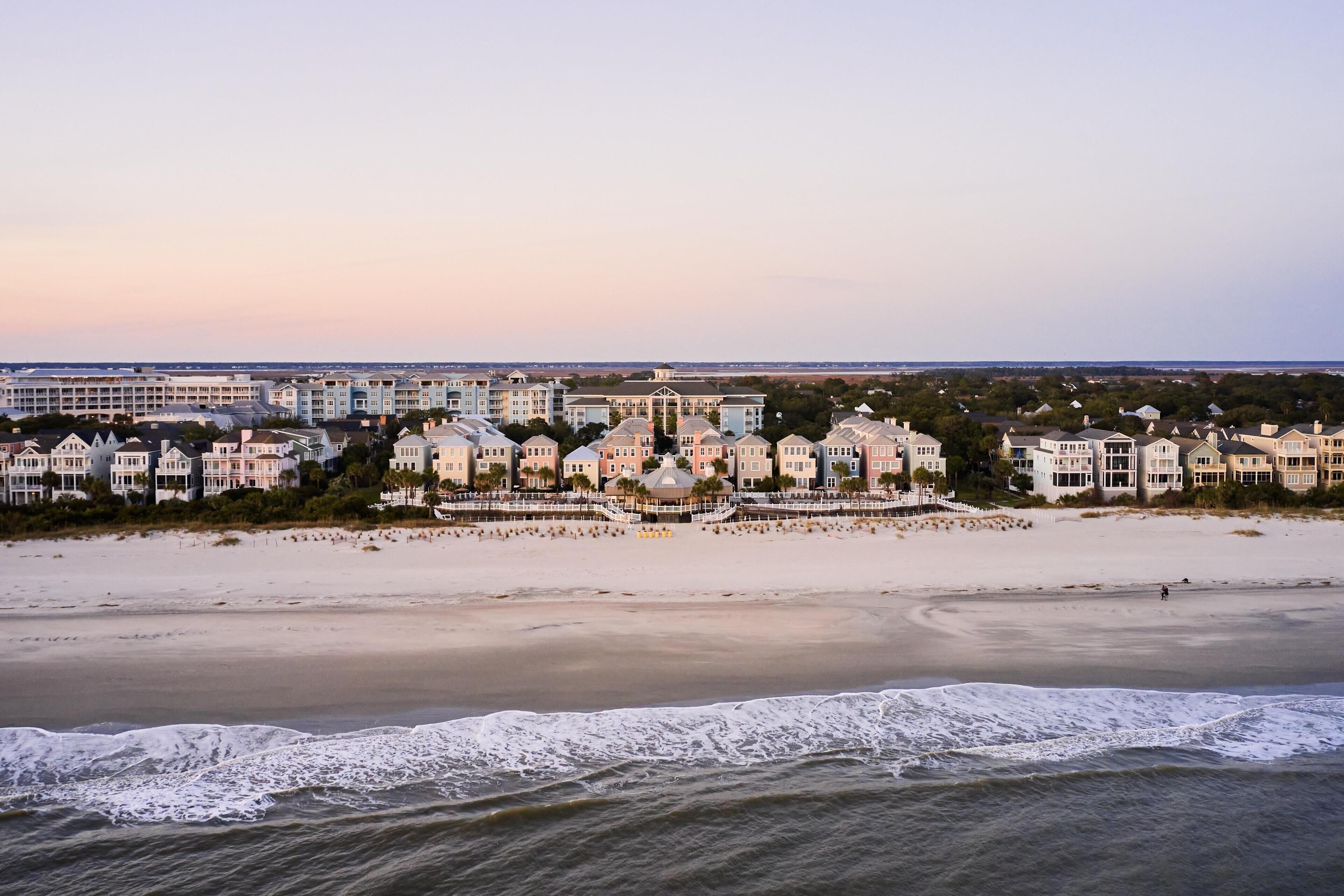 A coastal hotel with beachfront rooms, a sandy beach, and ocean waves.