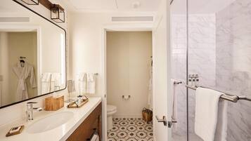 A modern bathroom with a large mirror, white sink, and a shower area.