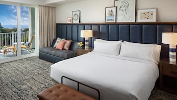 Une chambre d’hôtel avec un grand lit, un canapé, un fauteuil, une table de chevet et un balcon avec vue.