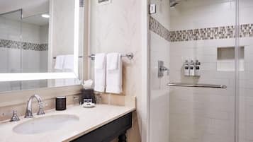 A modern bathroom with a large mirror, a sink, a glass shower enclosure, and a towel rack.