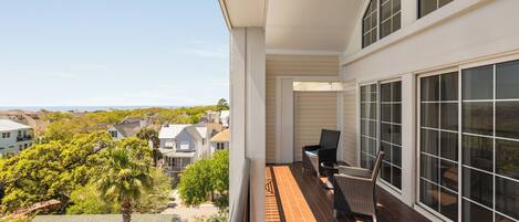 A balcony with a view of the neighborhood, a chair, and a small table.