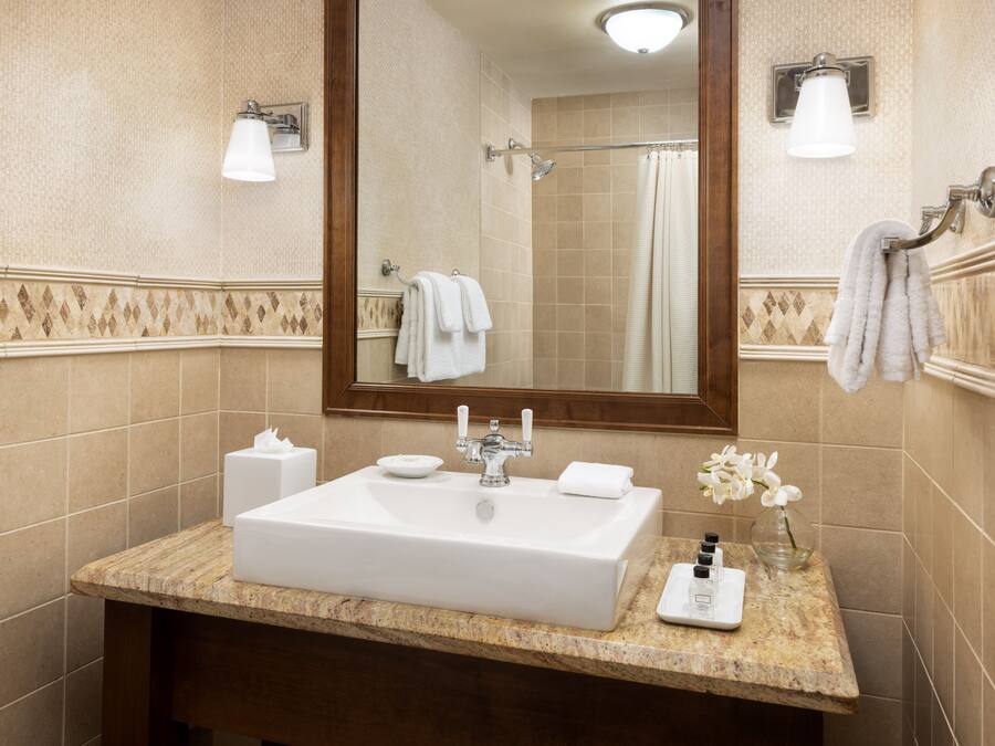 Un baño con un espejo grande, un lavamanos con toallero y zona de ducha.