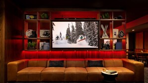 A cozy living room with a large flat-screen TV, a leather sofa, and a small coffee table. - Elevation Hotel & Spa (Crested Butte)