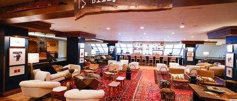 A spacious lobby with a red carpet, multiple seating areas, and a piano.