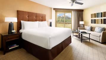 Une chambre d’hôtel avec un grand lit, un canapé, une table basse et une vue sur les montagnes.