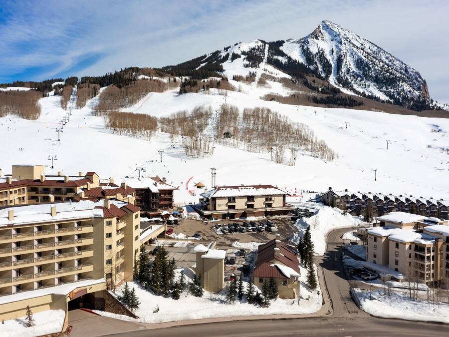 A ski resort with multiple buildings, a ski lift, and a mountain in the background.