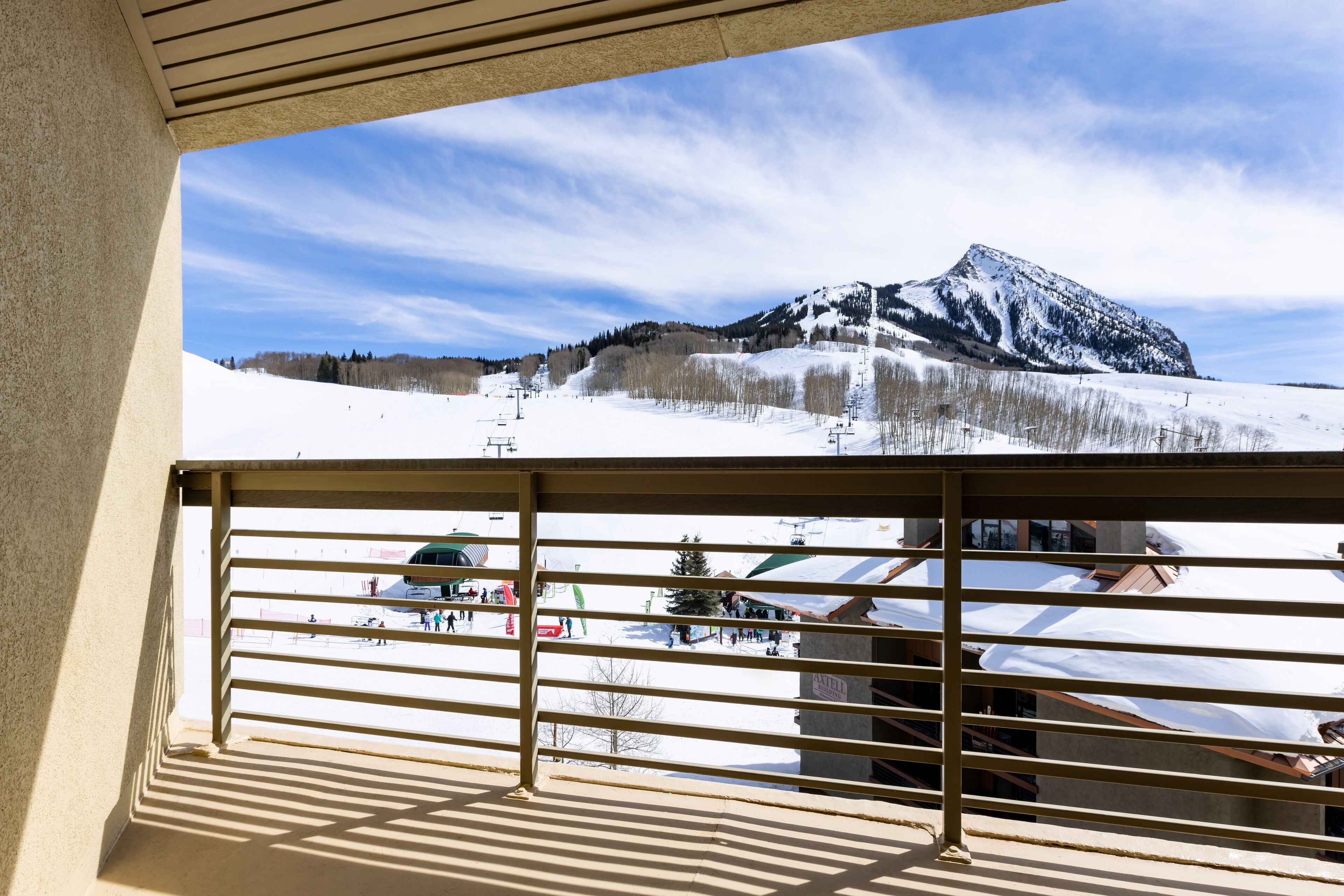 A balcony with a view of a snowy mountain landscape, including a ski lift and a building with a sloped roof.