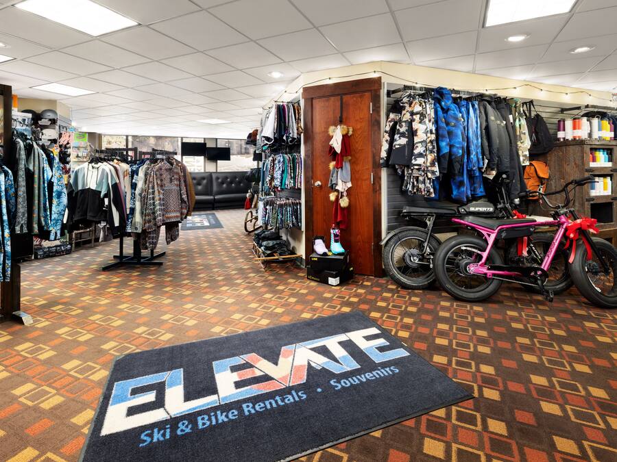 Uma loja com araras de roupas e um espaço de aluguel de bicicletas.
