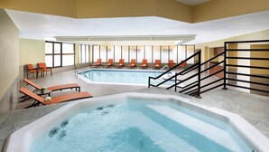 A large indoor swimming pool with a hot tub, surrounded by orange chairs and a staircase. - Elevation Hotel & Spa (Crested Butte)