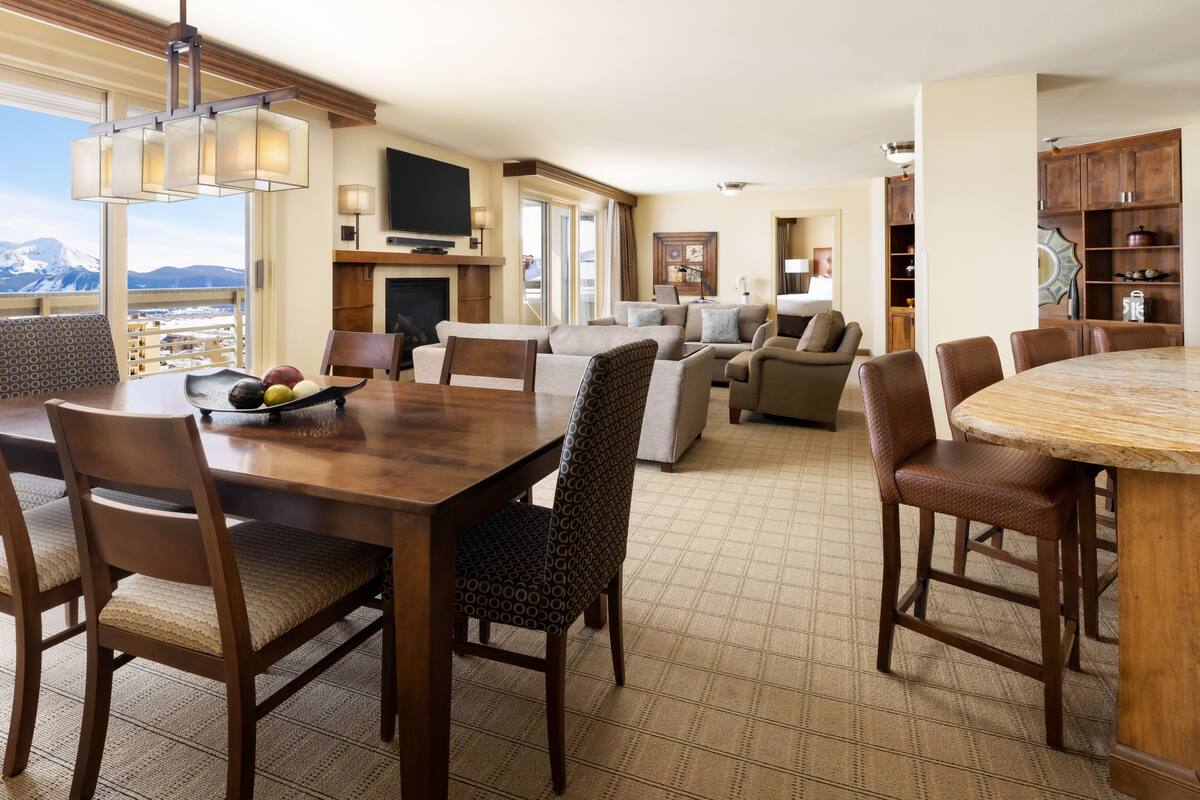 A spacious living room with a large wooden dining table, comfortable seating, and a fireplace.