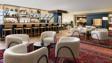 A bar area with stools and a bar counter, a seating area with chairs and a table, and a fireplace in the background.