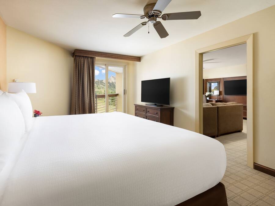 Une chambre d’hôtel avec un grand lit, un ventilateur de plafond, une télévision et une vue sur l’extérieur.