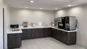 A modern kitchen with dark cabinets, a white countertop, a sink, a coffee machine, and a refrigerator. - Days Inn by Wyndham Wagoner (Wagoner)