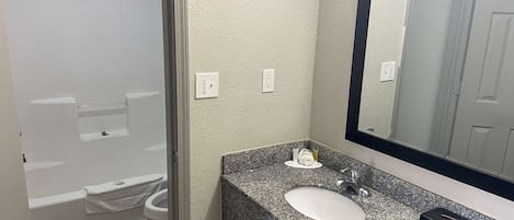 Un baño con una bañera blanca, un lavamanos blanco y una encimera de granito.