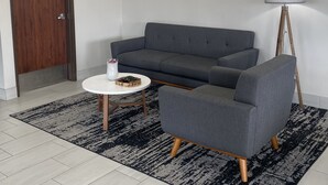 A modern living room with a grey sofa, a round coffee table, and a unique spherical light fixture. - Days Inn by Wyndham Wagoner (Wagoner)