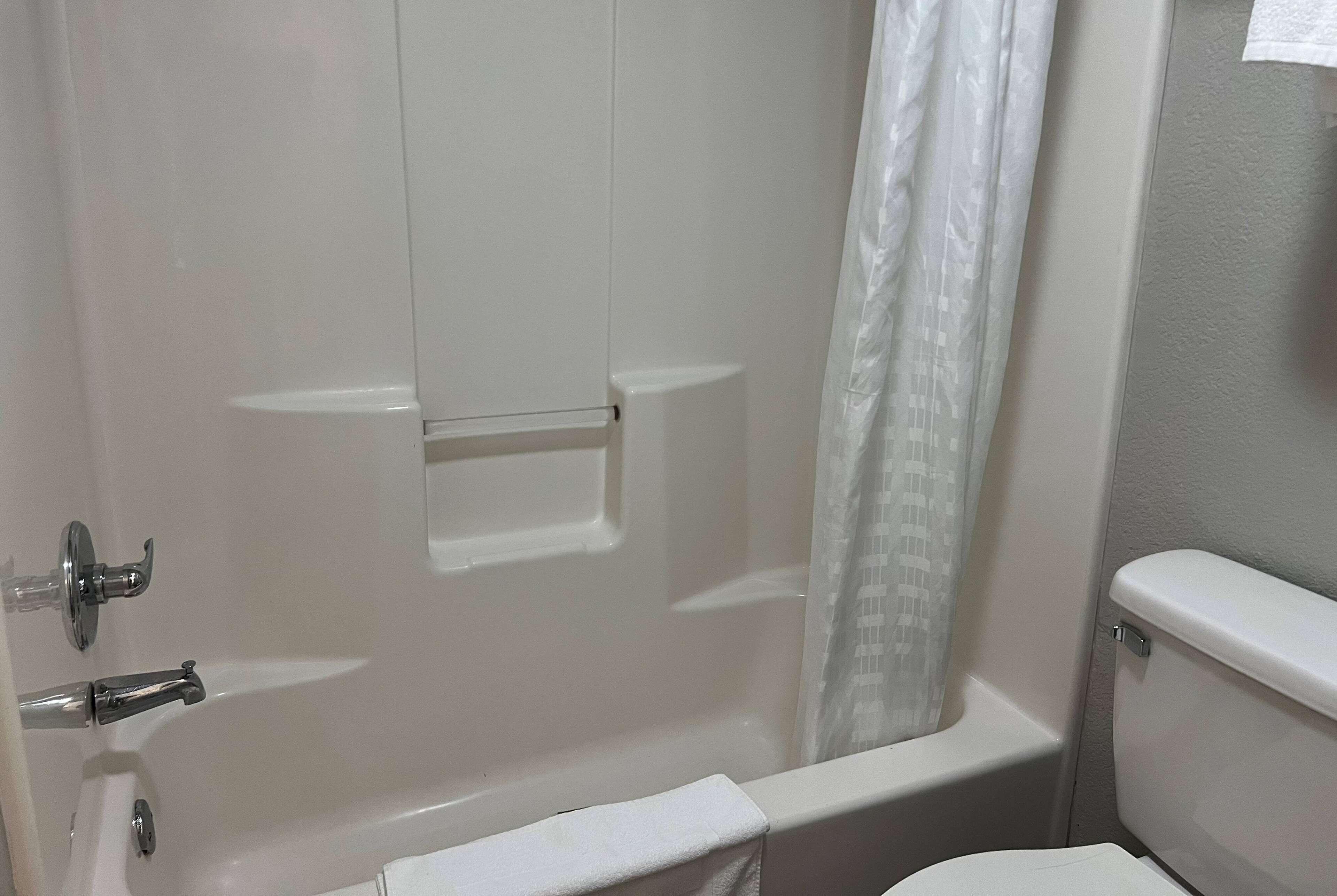 Une salle de bain avec une baignoire, des toilettes et un rideau de douche.