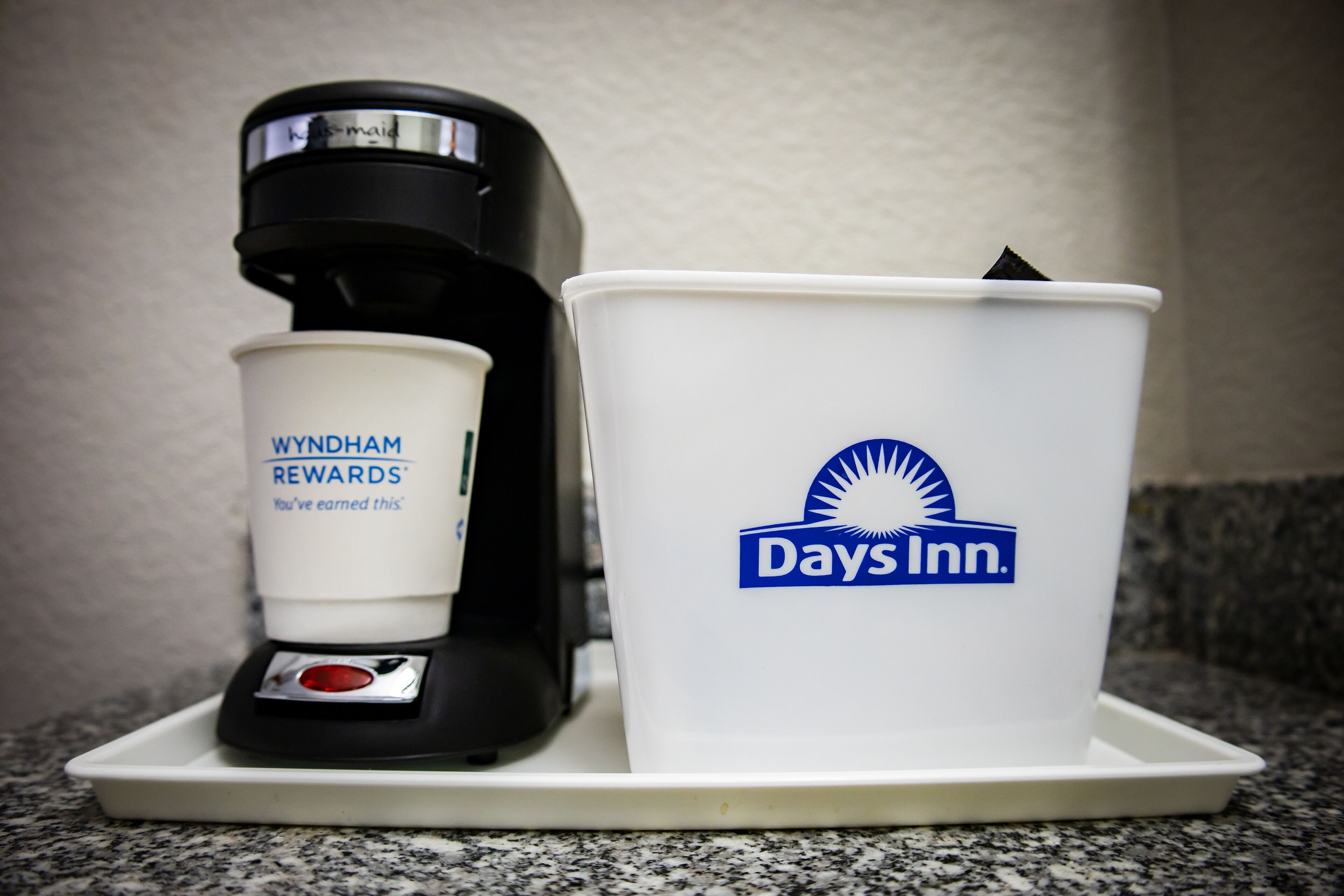 Una cafetera y un recipiente con el logotipo de Days Inn sobre una encimera.