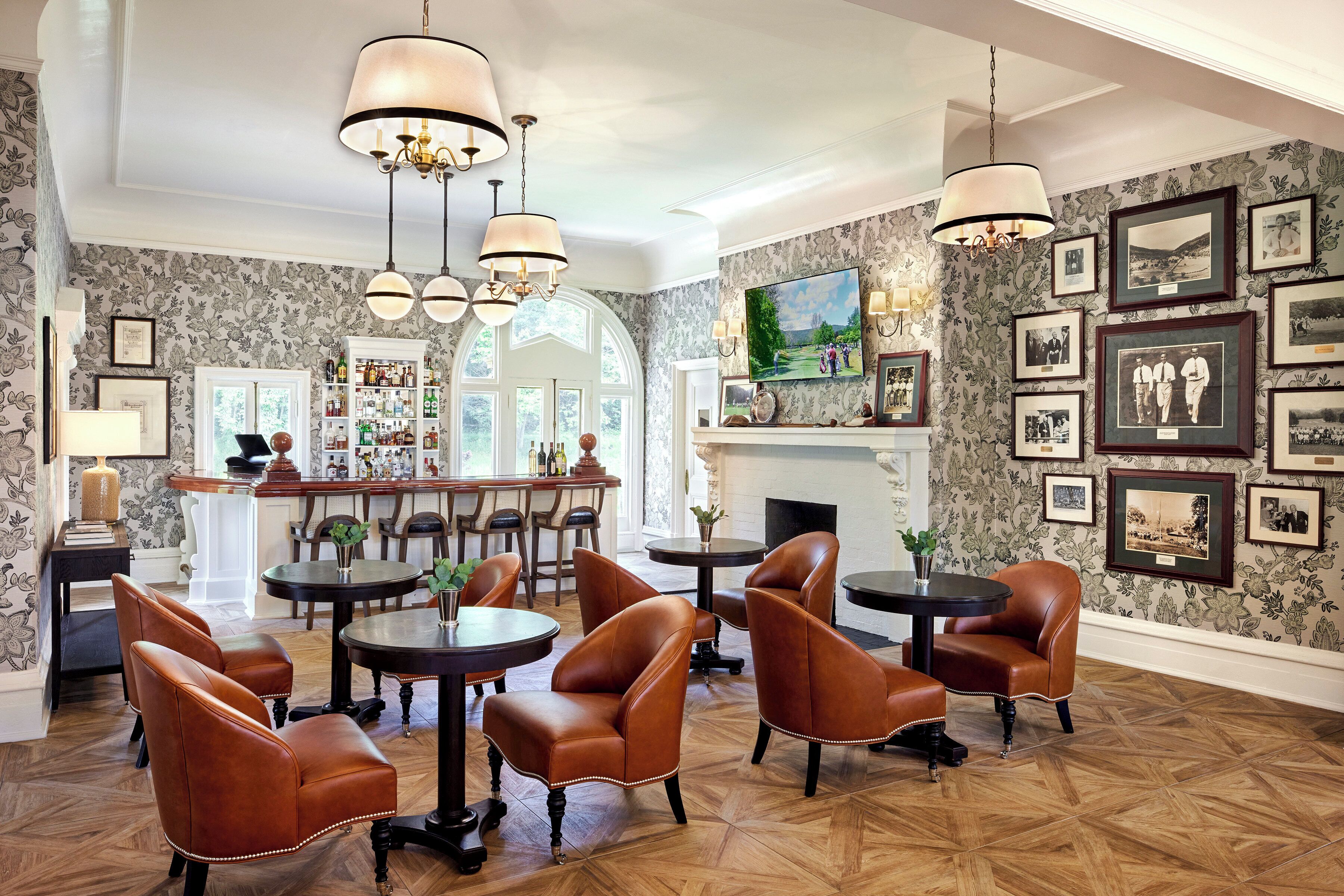 A spacious room with leather chairs, a bar area, and a fireplace.