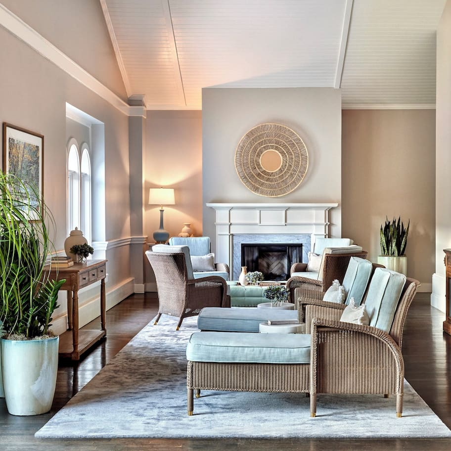 A spacious living room with a fireplace, comfortable seating, and large potted plants.