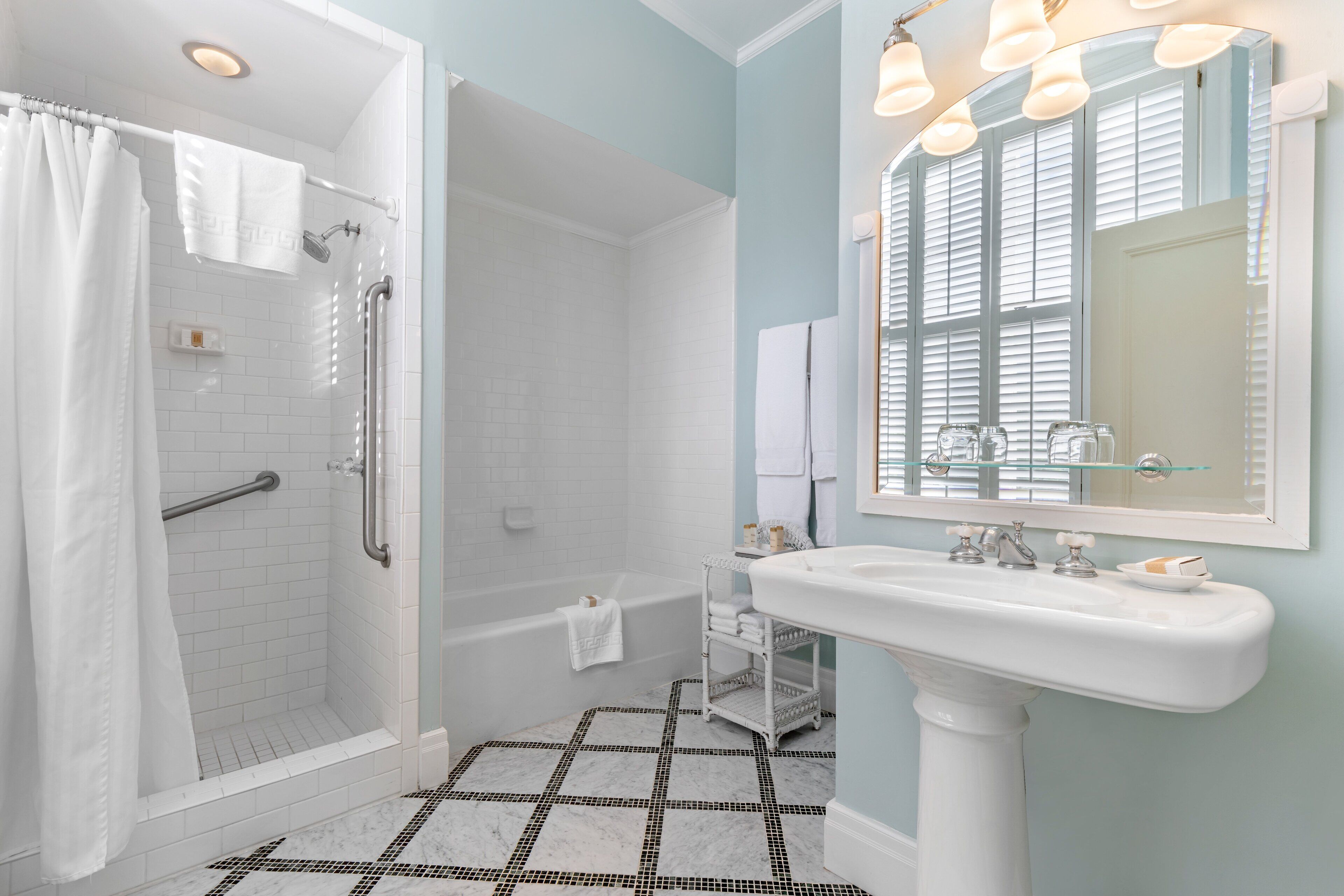 A bathroom with a shower, a bathtub, a sink, and a mirror.