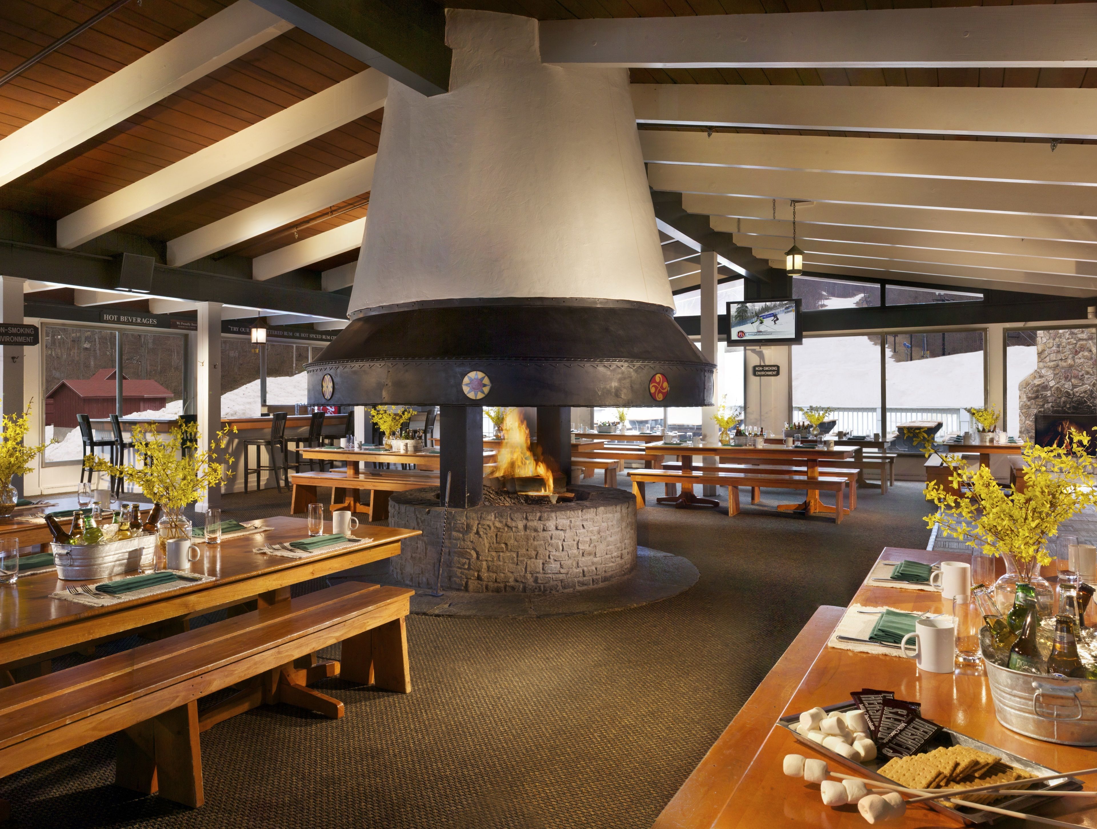 Un restaurant doté d’une grande cheminée en pierre, de tables et de bancs en bois.