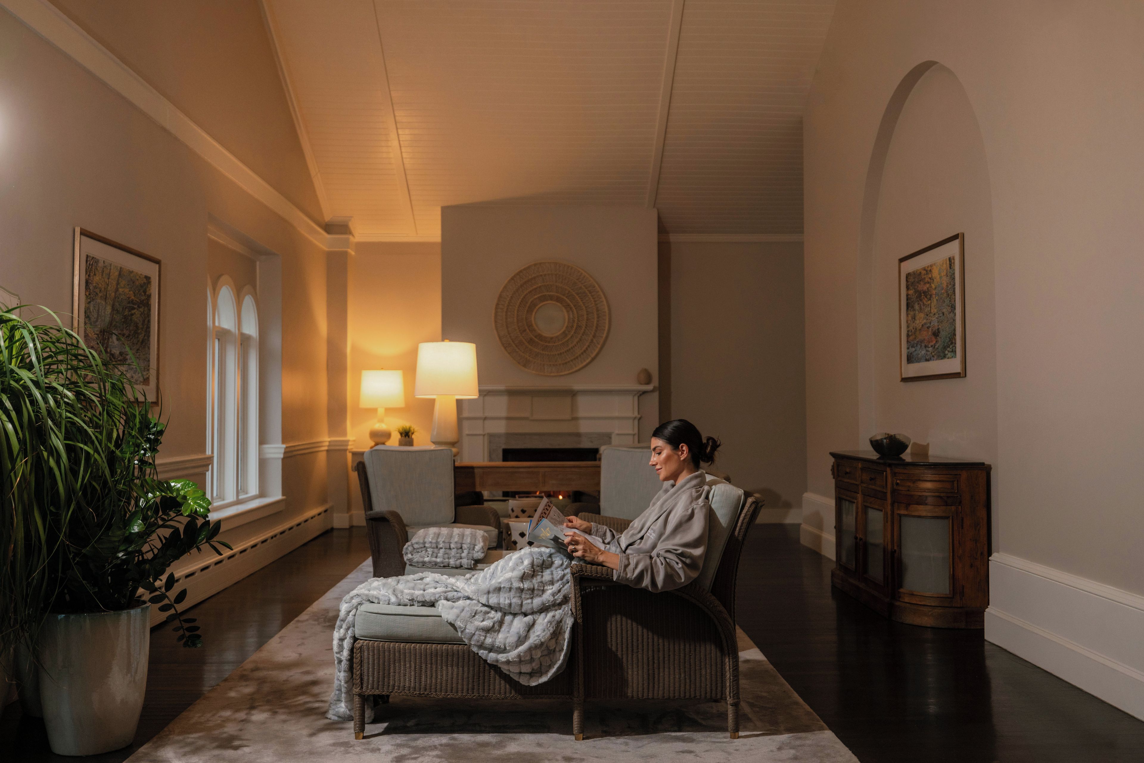 A cozy living room with a fireplace, a comfortable sofa, and a reading area.