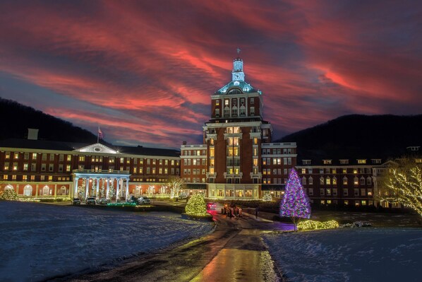 A large building with a central tower, multiple windows, and a snow-covered ground.