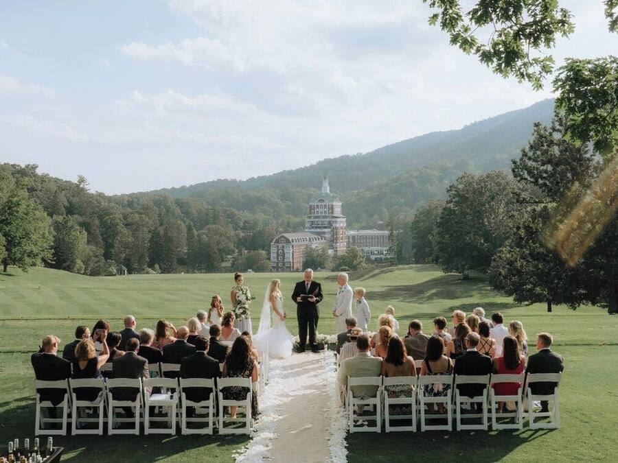 A wedding ceremony on a golf course with a large building in the background.