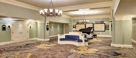 Une pièce spacieuse agrémentée d’un magnifique lustre, d’un piano et d’un grand tapis décoratif.