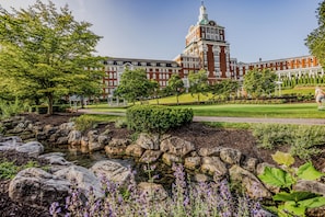 A large building with a prominent tower and a well-maintained garden with a pond and rocks. - The Omni Homestead Resort & Spa (Hot Springs)