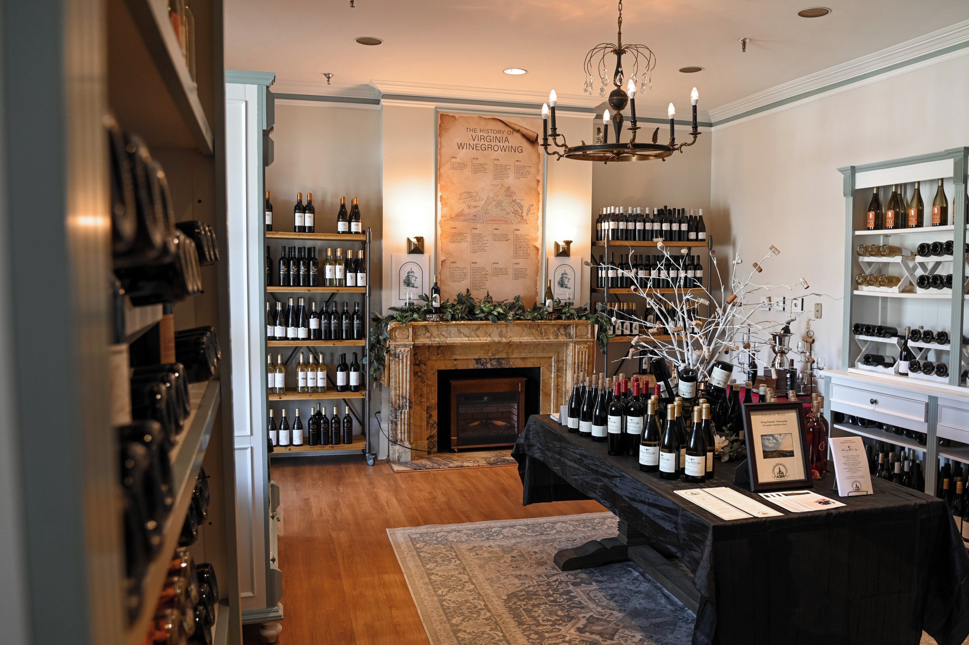 A wine cellar with shelves of wine bottles, a fireplace, and a chandelier.