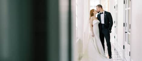 A couple in wedding attire in a hallway with a checkered floor and white walls.