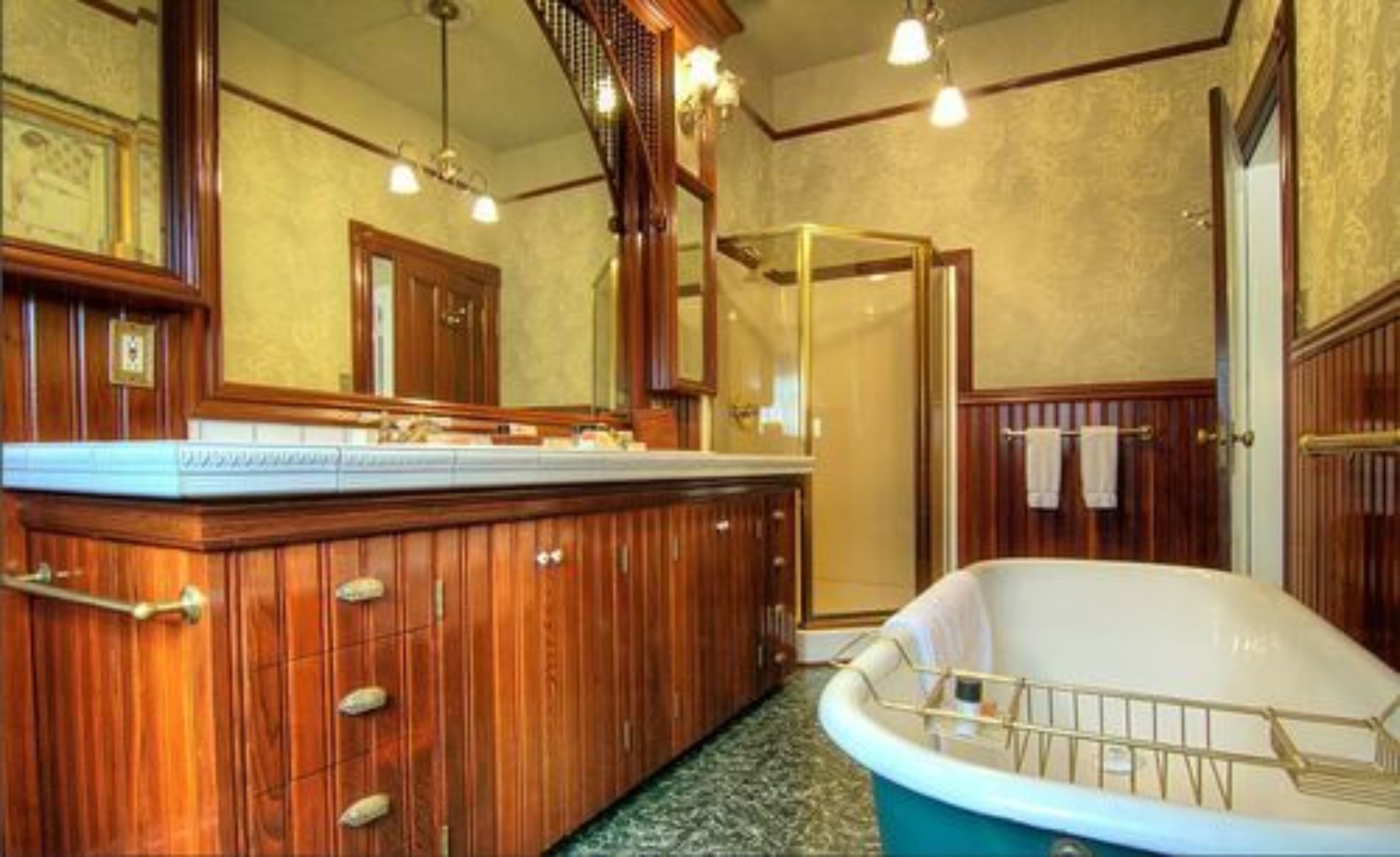 Een badkamer met een houten wastafelmeubel, een vrijstaand bad en een douchecabine met glazen wanden.