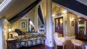 A bedroom with a large bed, a chair, a dresser, and a fireplace. - Gingerbread Mansion Inn (Ferndale)
