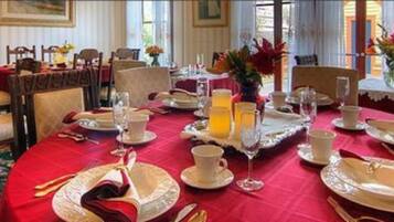 A dining area with red tablecloths, white plates, and silverware. There are floral centerpieces on the tables.