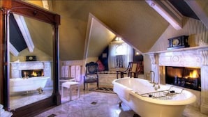 A spacious bathroom with a freestanding bathtub, a large mirror, and a fireplace. - Gingerbread Mansion Inn (Ferndale)