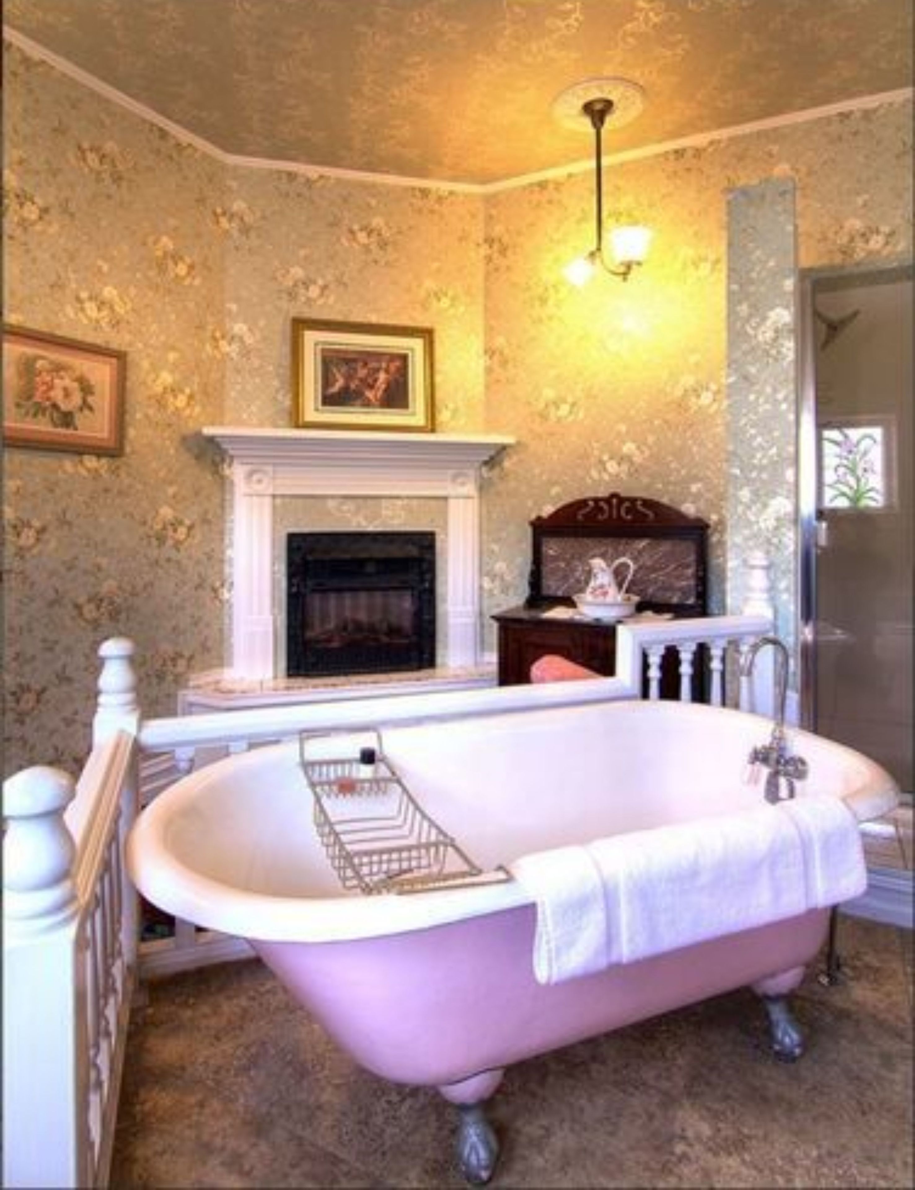 A bathroom with a freestanding bathtub, a fireplace, and a mirror.