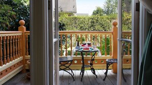 An outdoor patio with a wooden table set for tea, surrounded by a wooden fence and a view of greenery. - Gingerbread Mansion Inn (Ferndale)