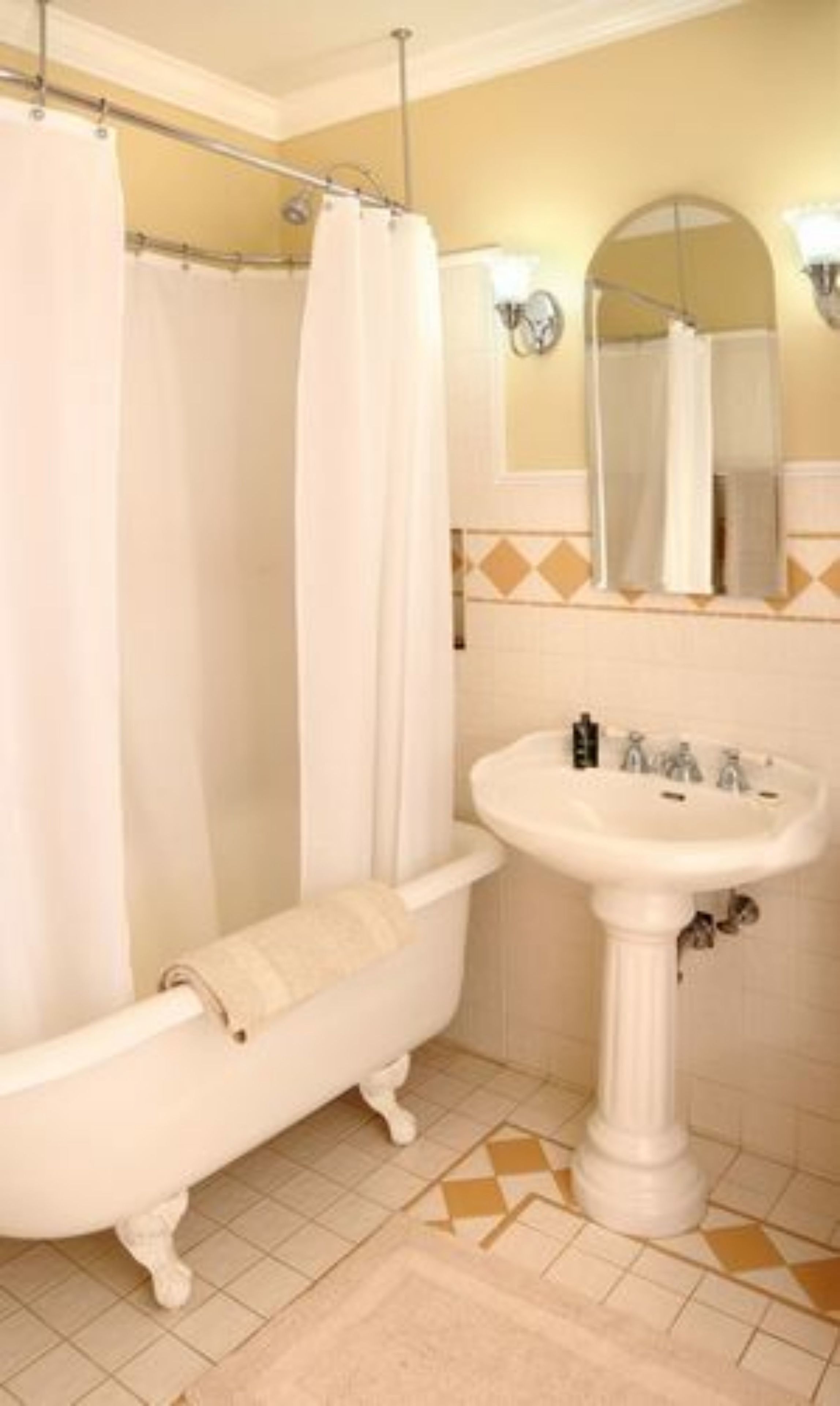 A bathroom with a clawfoot bathtub, a pedestal sink, and a mirror above the sink.