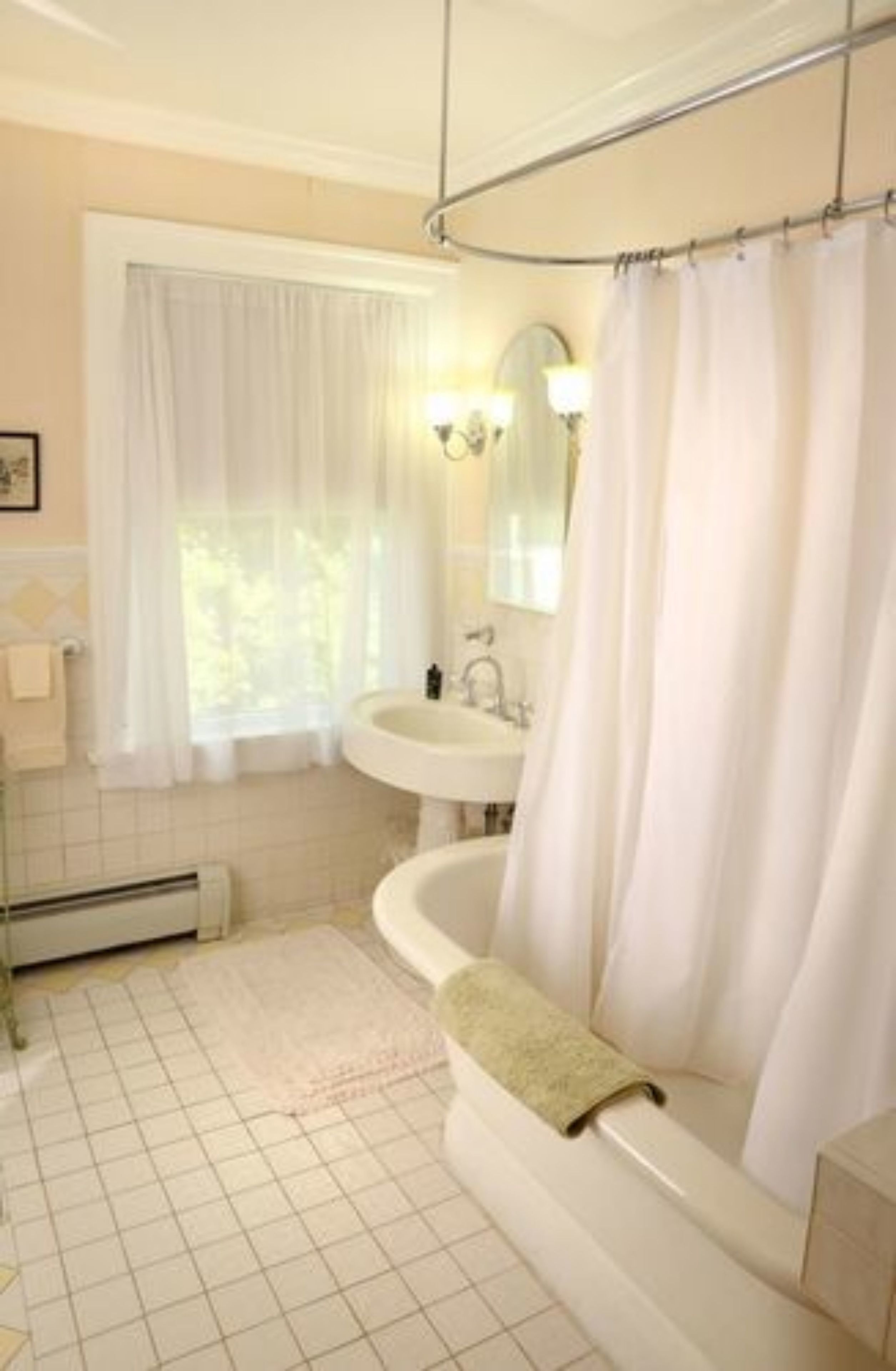 Un baño con bañera, lavamanos y ventana con cortinas.