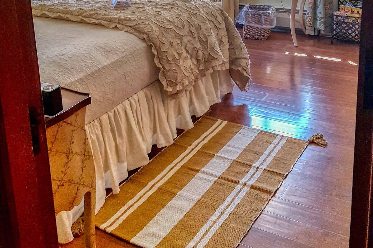 A bedroom with a bed, a ceiling fan, a television, a chair, a table, and curtains.