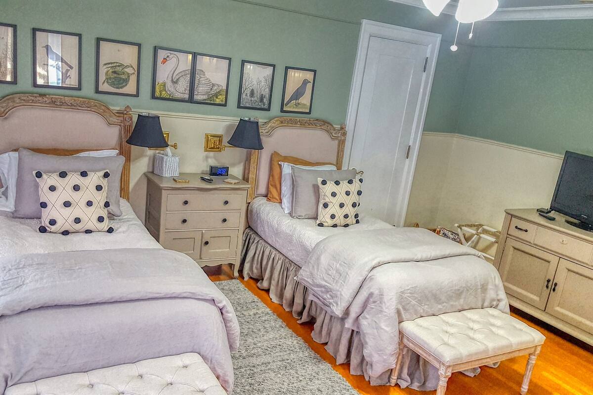 A bedroom with two beds, a nightstand, a dresser, and a television.