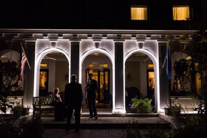 A hotel entrance with three illuminated arches and a flag.