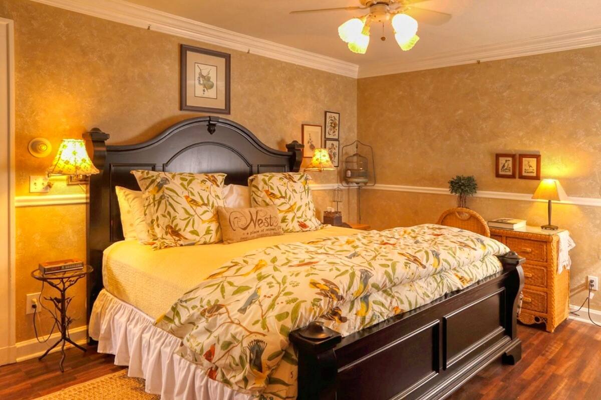 A bedroom with a bed, bedside lamps, a nightstand, and a ceiling fan.