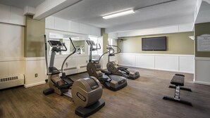 A fitness center with treadmills, elliptical machines, and a bench.