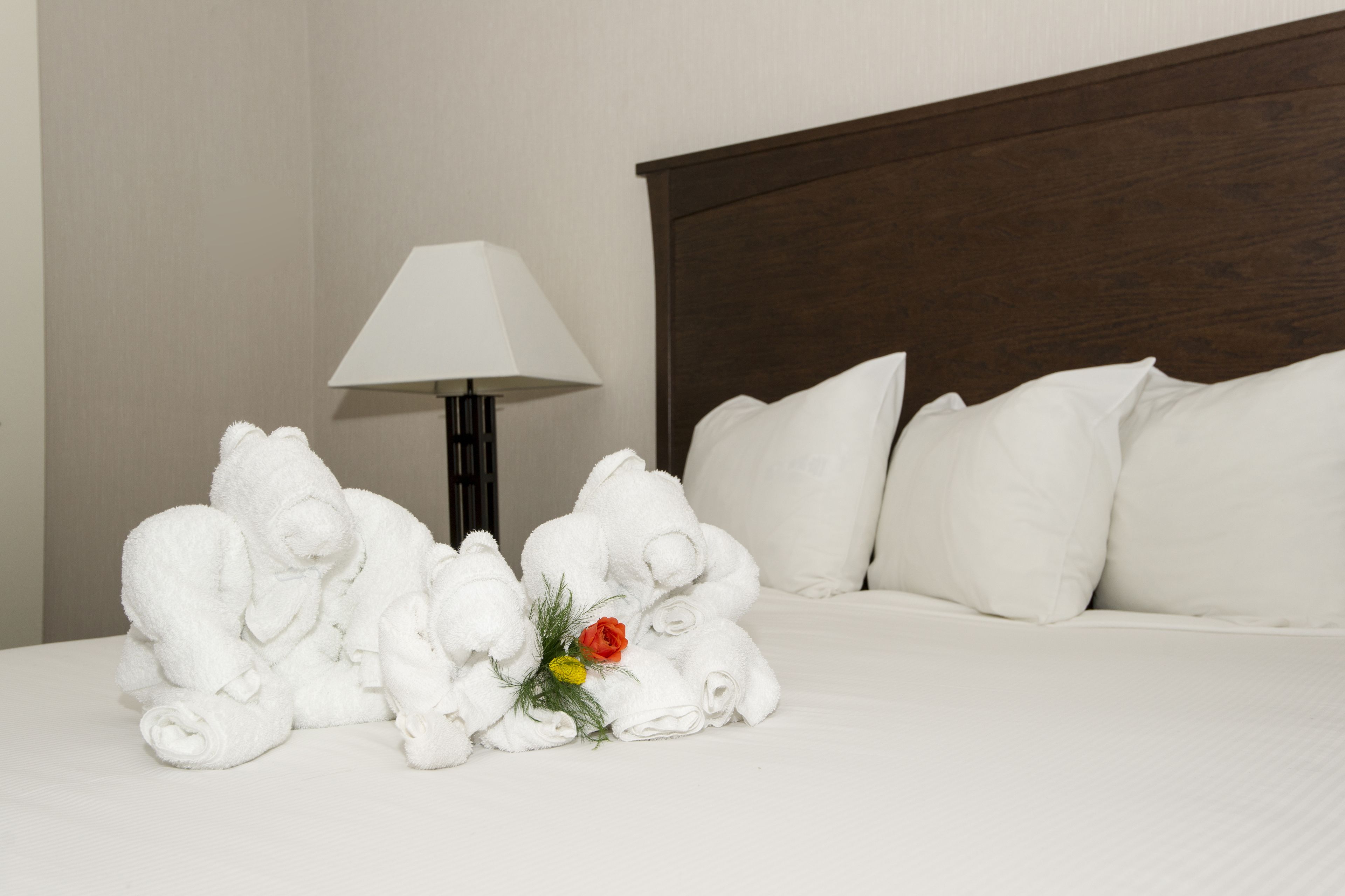 A neatly made bed with white pillows and a floral arrangement on the side.