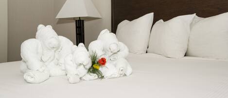A neatly made bed with white pillows and a floral arrangement on the side.